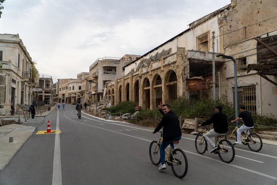 Three young men on rental bikes, one making a peace sign